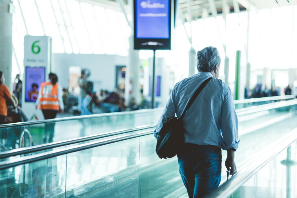 An adult male walking upon arrival on an airport travelator, captured in a modern and well-lit terminal.