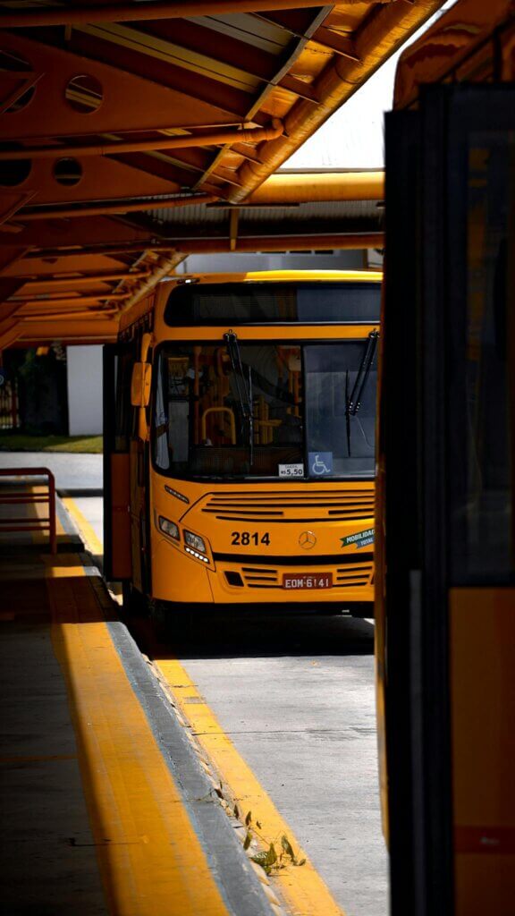Yellow city bus parked at an outdoor urban station terminal during the day. PH Transit Lines
