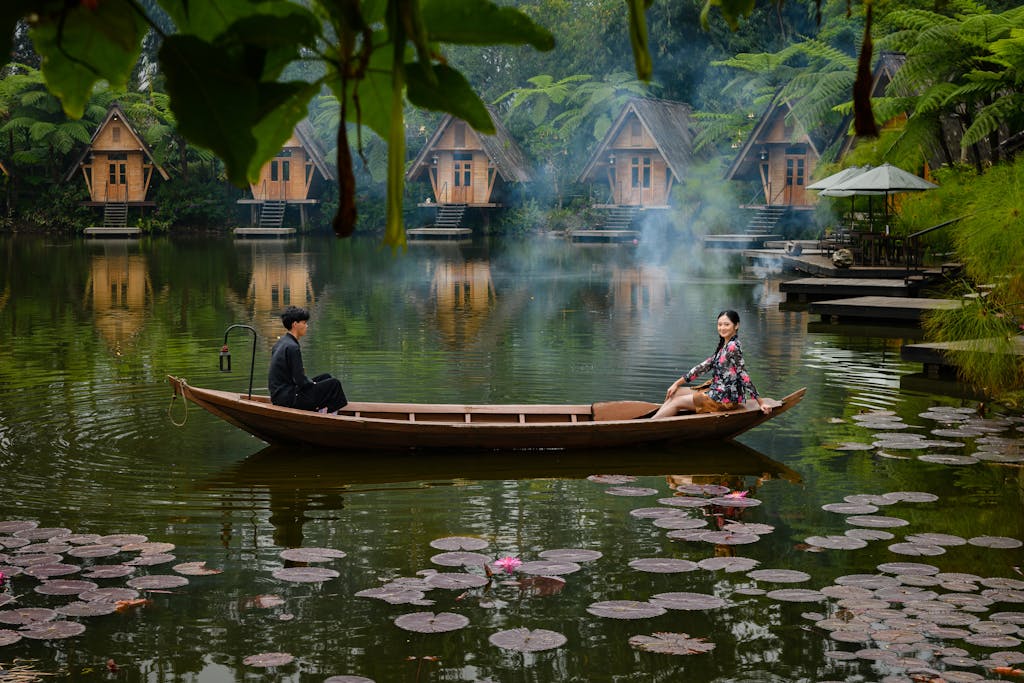 A couple enjoys a serene boat ride on a lily pond near cabin accommodations in Jawa Barat, Indonesia.