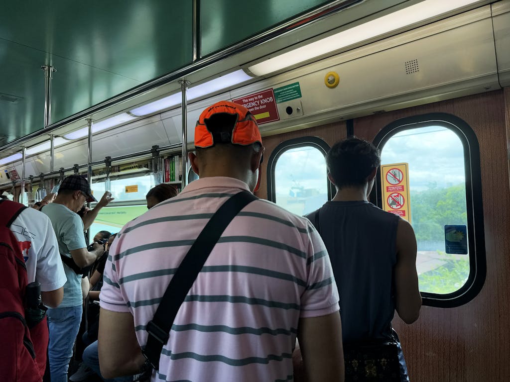 A view inside a Metro Manila train with passengers standing, capturing the urban commuter experience. Go