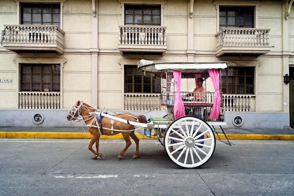 A horse-drawn carriage known as a 'kalesa' in Manila, highlighting traditional transport in a bustling cityscape. Metro Manila tourist corridors and day-trip gateways.