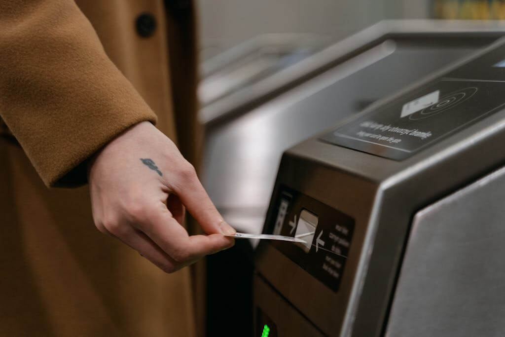 A person inserting a beep card into a turnstile at a train station, showcasing public transportation usage.