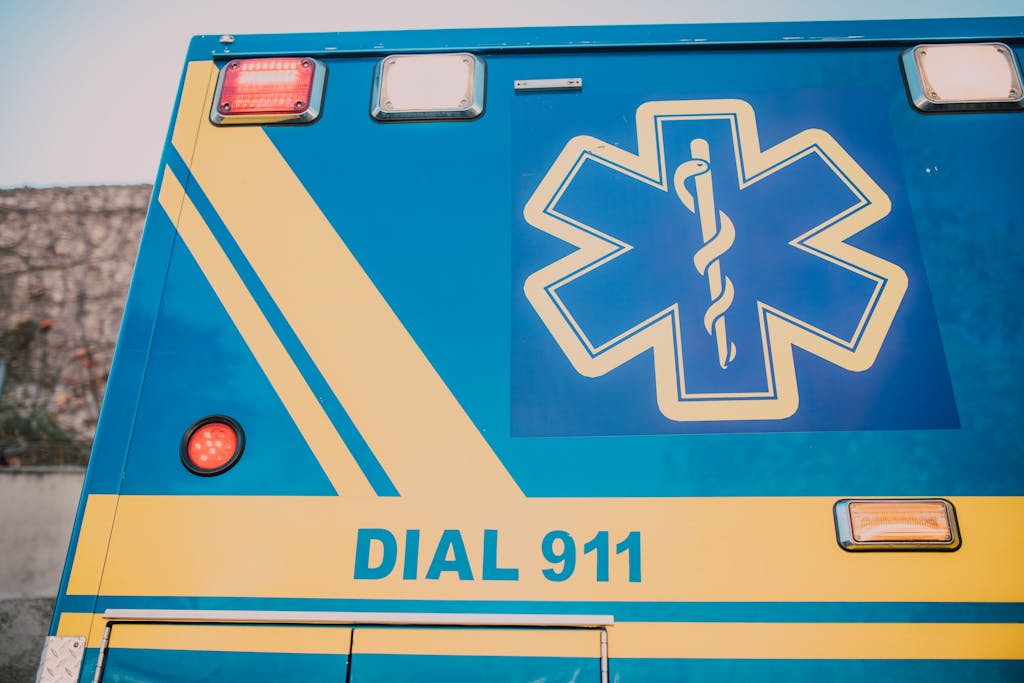 Close-up of an ambulance with star of life symbol and 'Dial 911' text. National Emergency hotlines