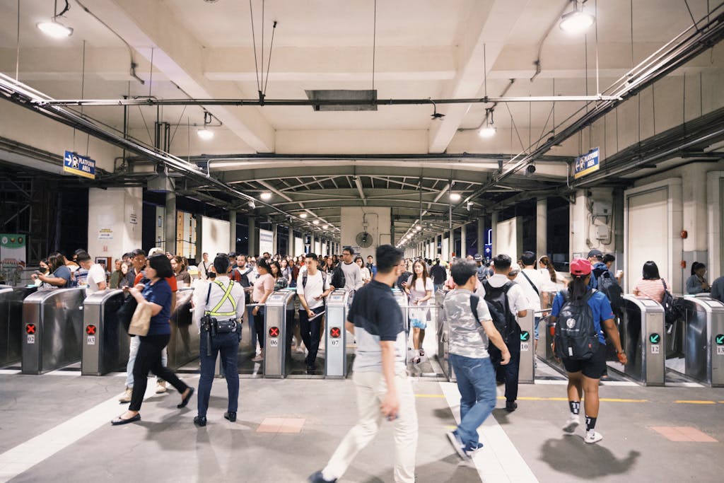Crowds of commuters pass through turnstiles at a bustling subway station indoors during rush hours.
