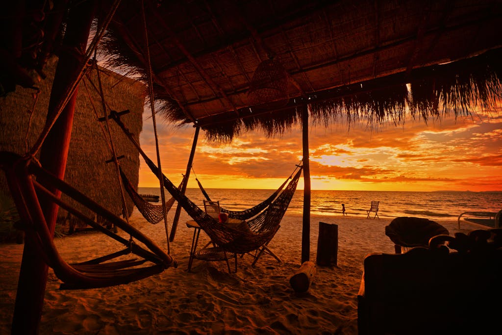 A serene sunset view at a beachside hut in Koh Kong, Cambodia, with hammocks and sandy shores. Koh Rong Cambodia tour