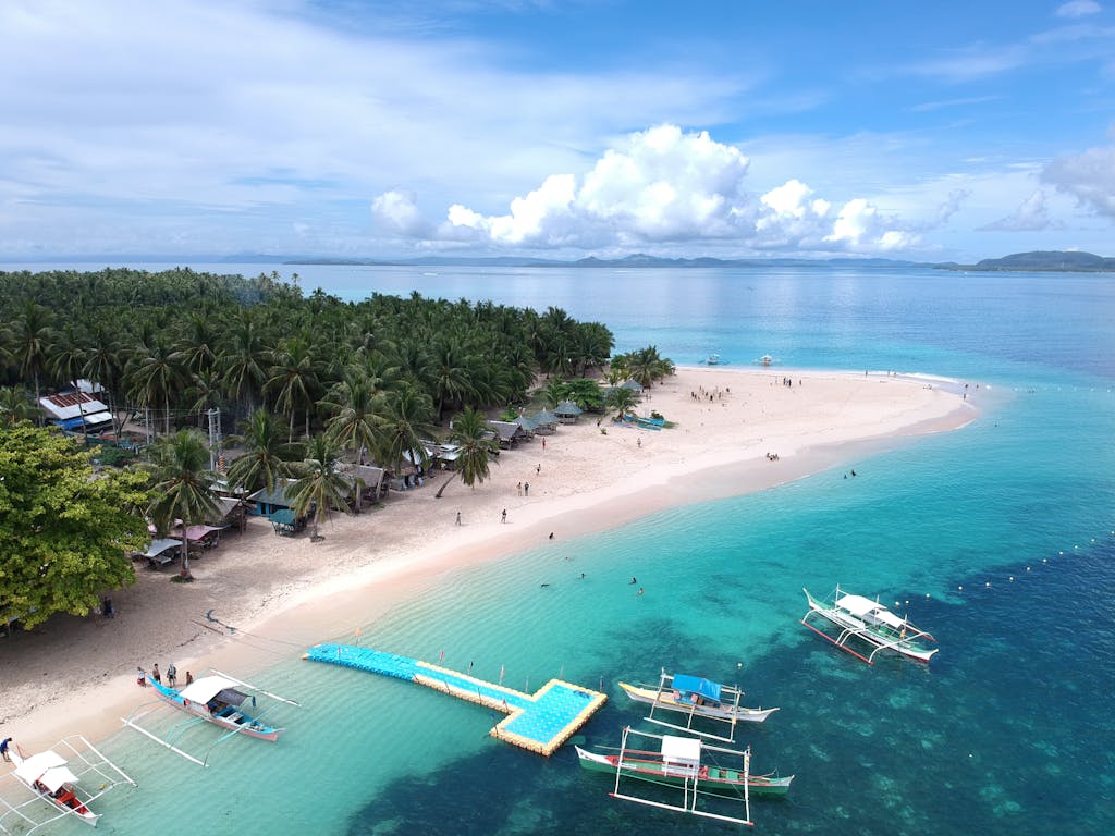 Aerial view of a stunning tropical beach in Caraga, Philippines, showcasing clear turquoise waters and lush surroundings. Philippines trip to famous beaches