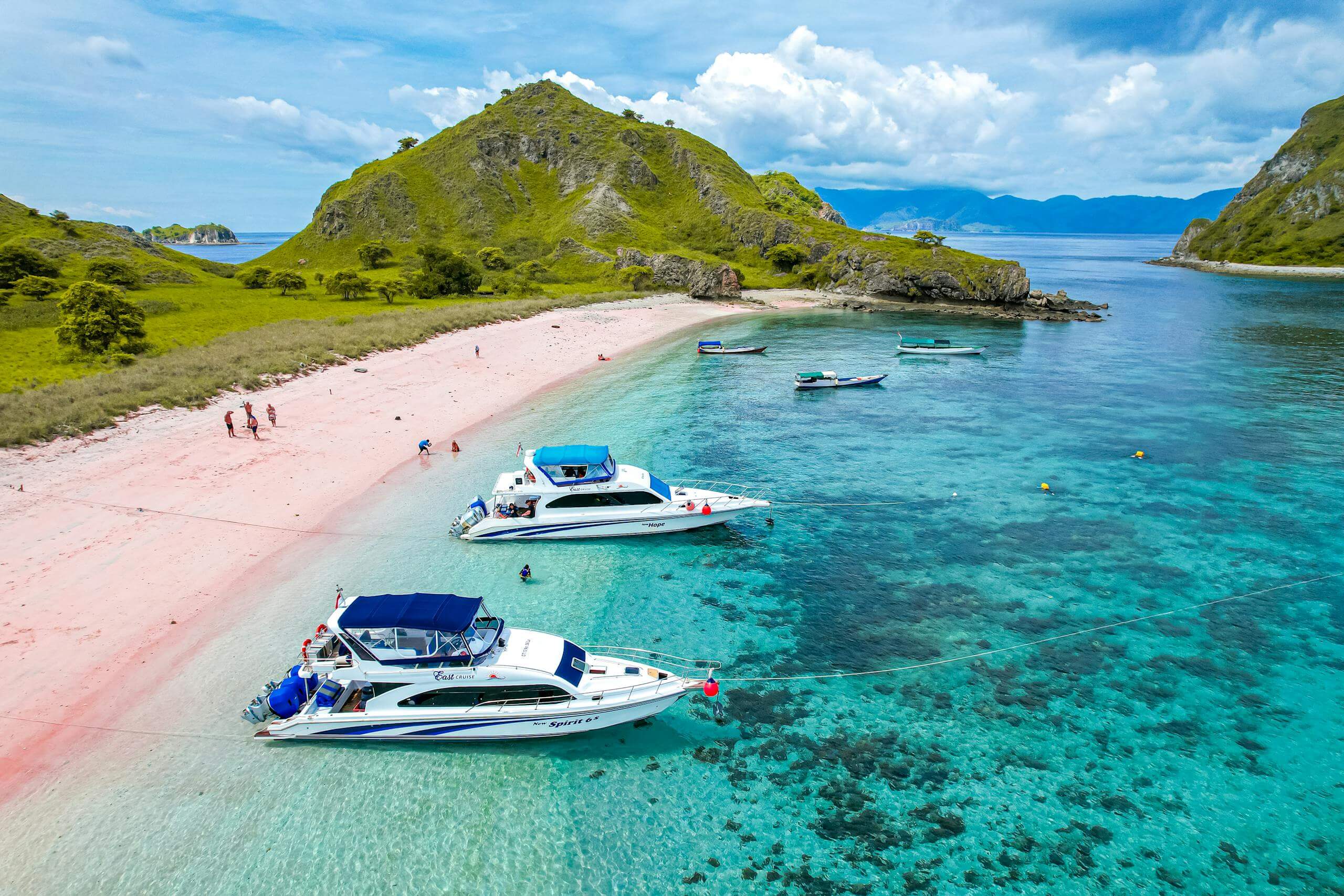 Aerial view of boats by the turquoise waters and pink sand beach at Komodo Island, Indonesia.