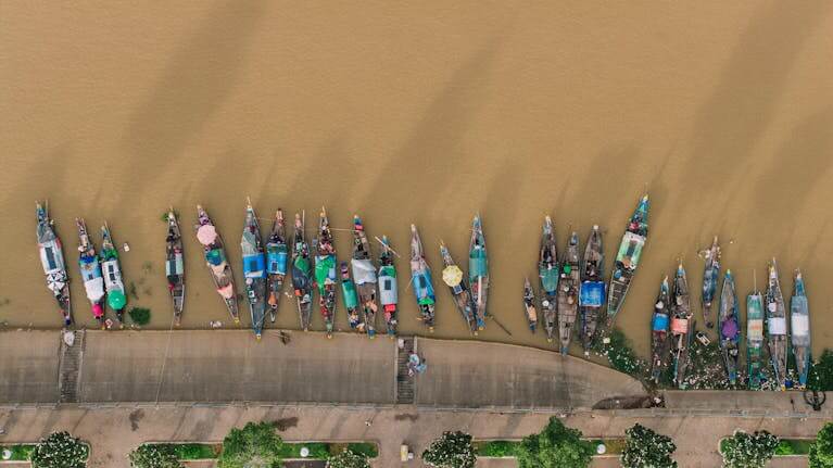 An aerial view of colorful boats moored along the riverbank of Phnom Penh, Cambodia.