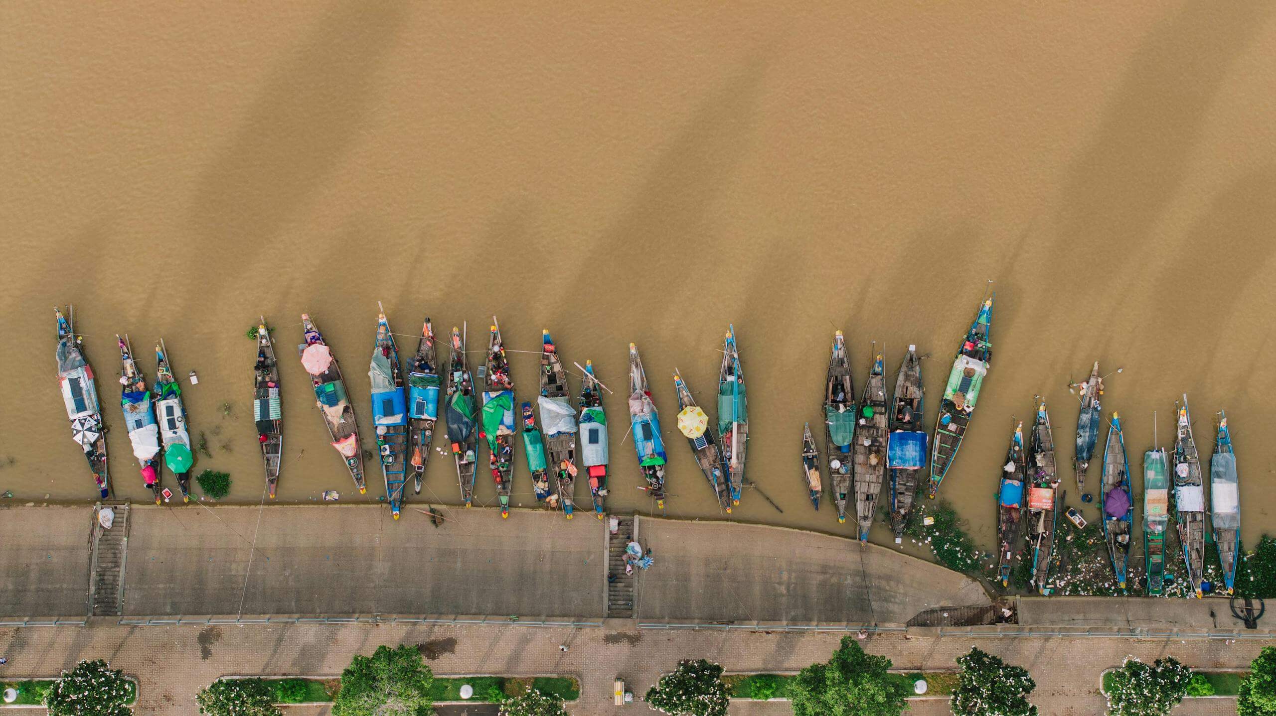 An aerial view of colorful boats moored along the riverbank of Phnom Penh, Cambodia.