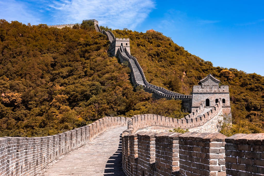 Majestic view of the Great Wall of China winding through verdant hills under a bright blue sky.