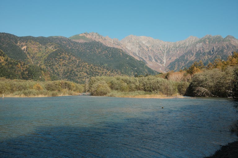 Peaceful lake view with mountain backdrop in Kamikochi National Park, Japan.