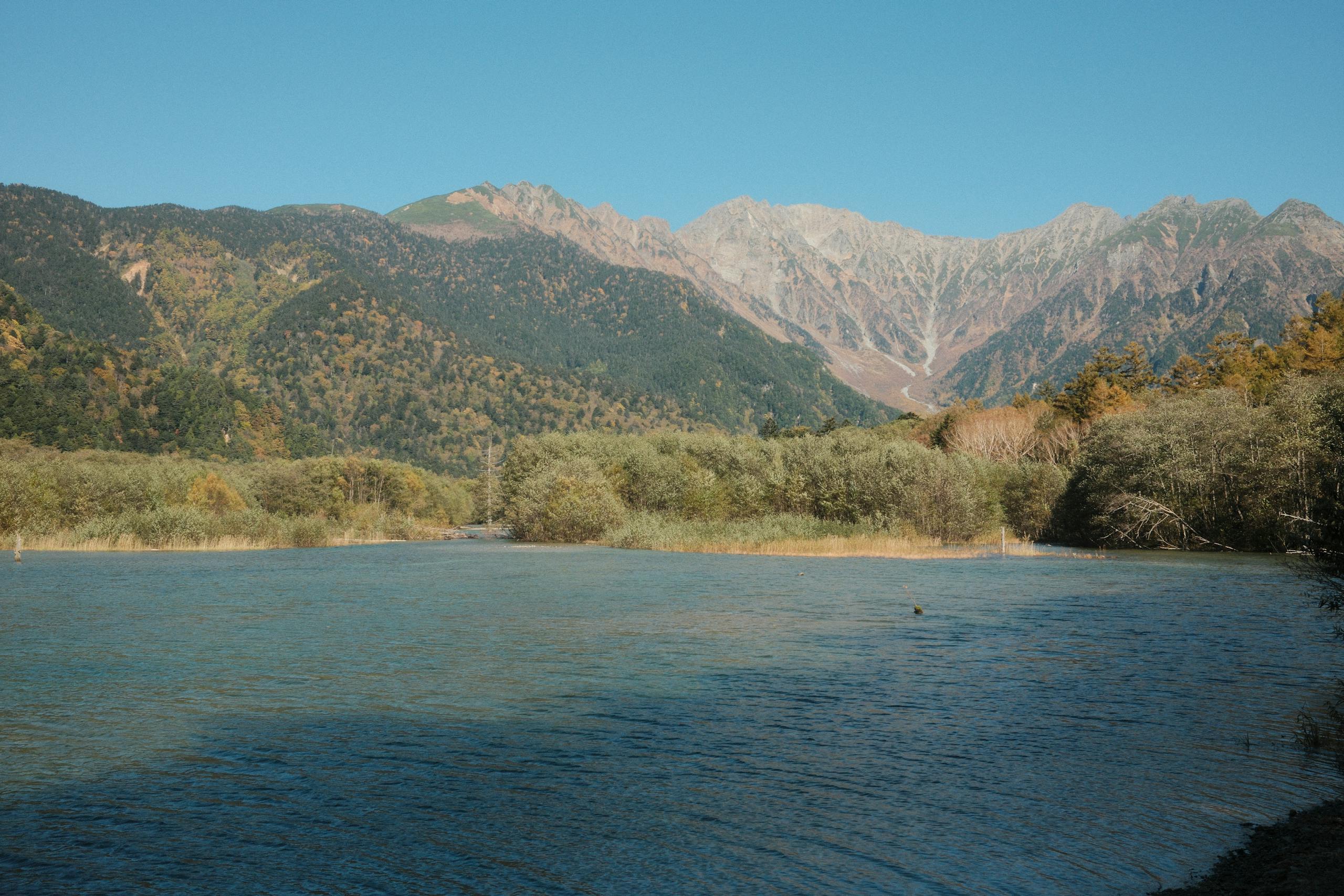 Peaceful lake view with mountain backdrop in Kamikochi National Park, Japan.