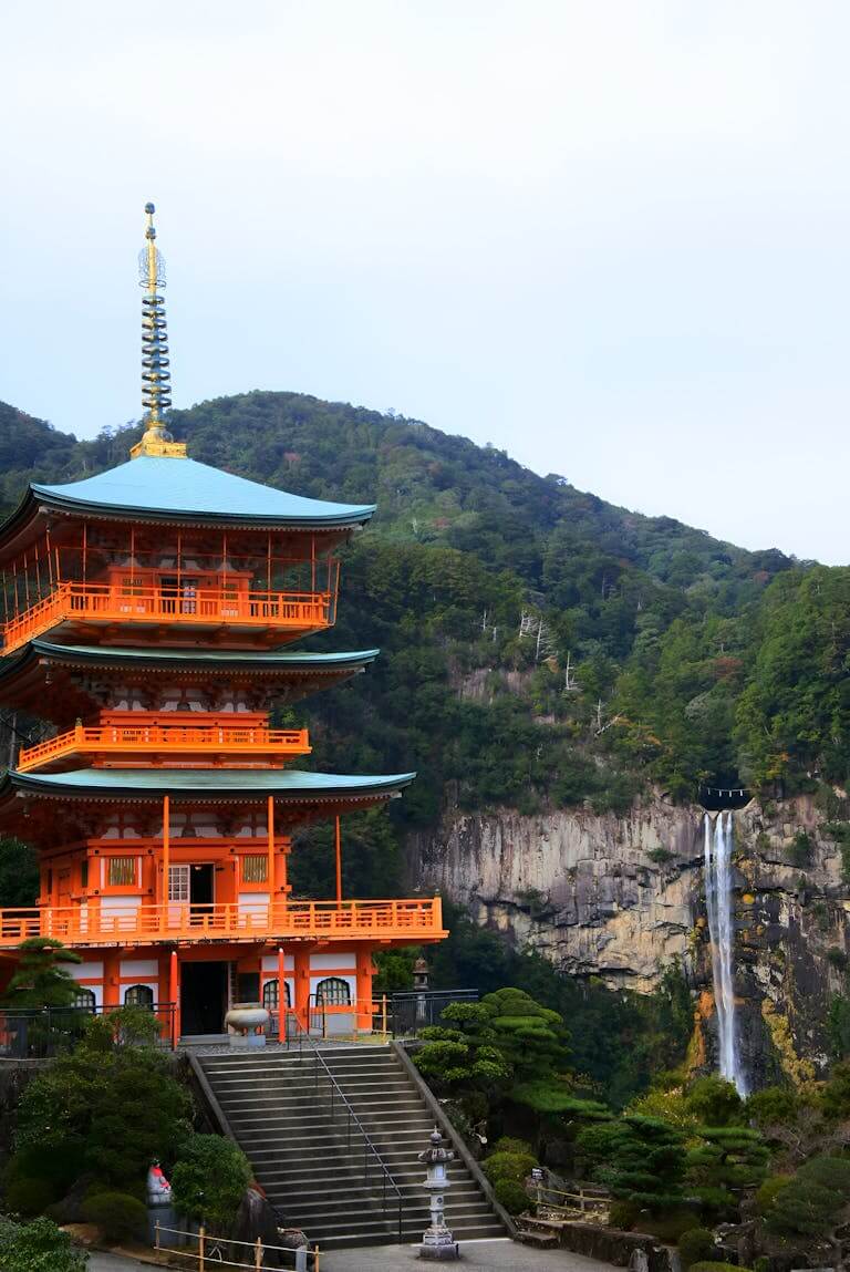 Seiganto-ji Temple with Nachi Falls in the foreground, located in Japan's lush mountains.