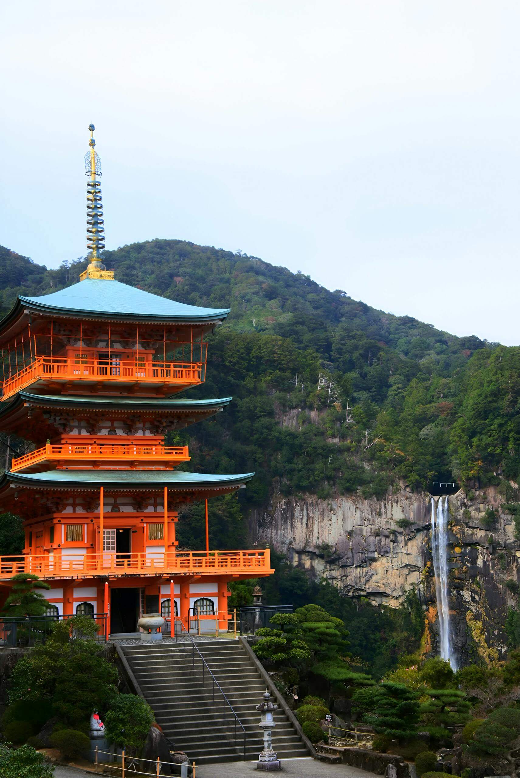 Seiganto-ji Temple with Nachi Falls in the foreground, located in Japan's lush mountains.