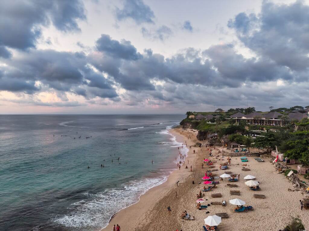 Stunning aerial view of a beach in Bali Indonesia tour with visitors at sunset.