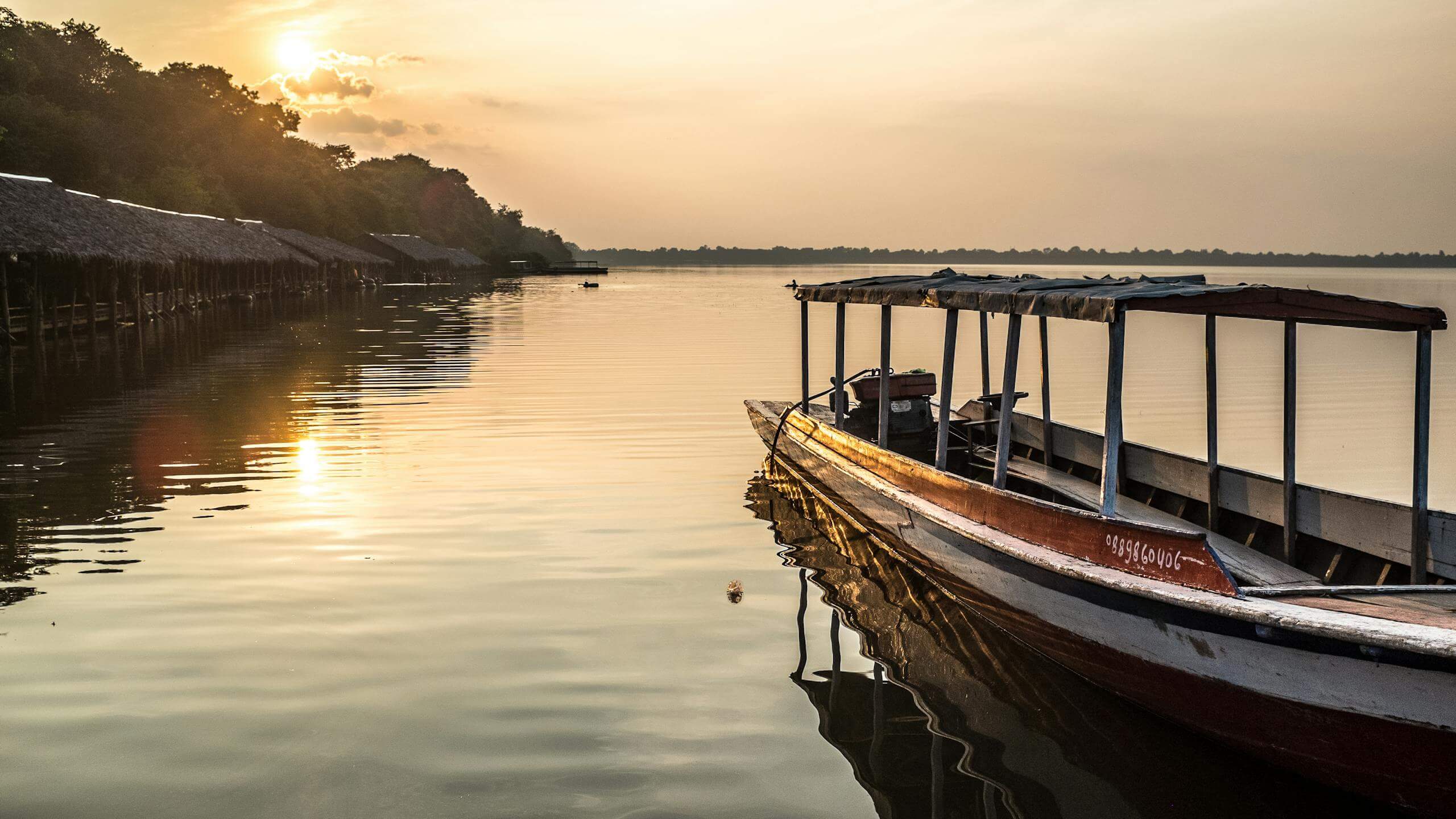 Tranquil scene of a wooden boat on a lake at sunset in Siem Reap Cambodia tour