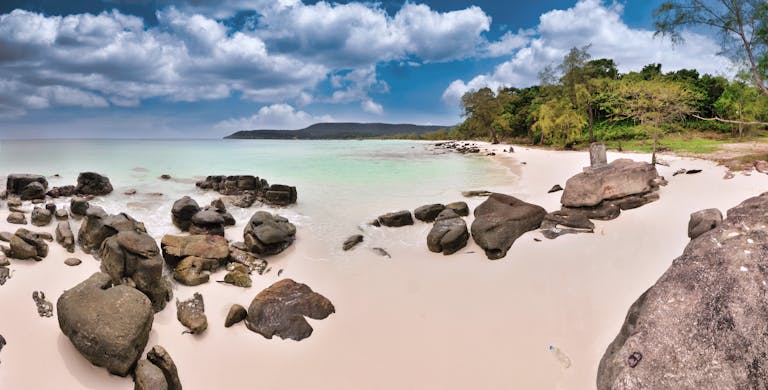 Tranquil Sok San Beach with clear waters and rocky shores in Cambodia.