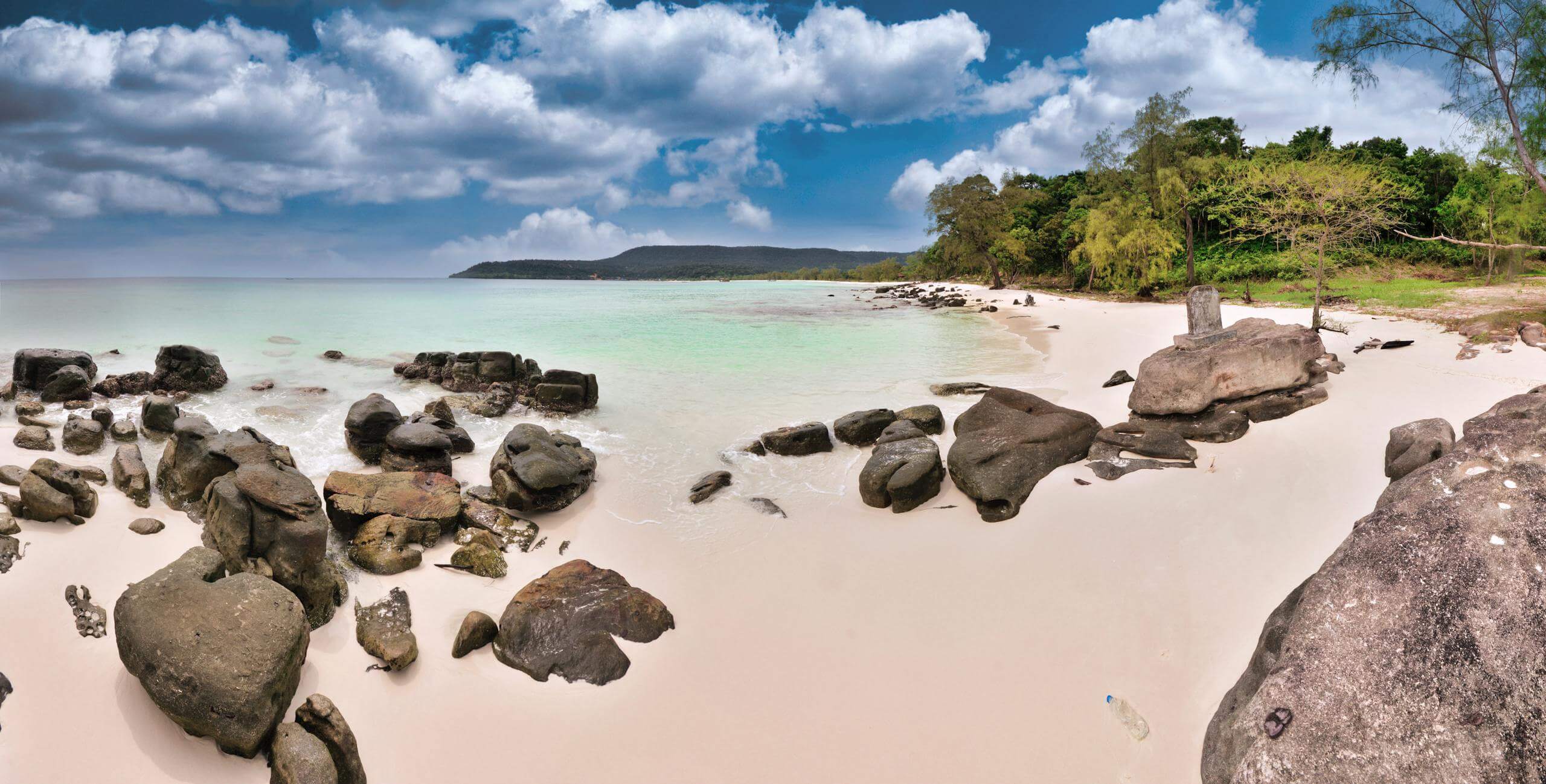 Tranquil Sok San Beach with clear waters and rocky shores in Cambodia.