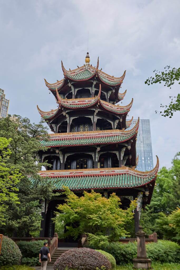 A beautiful multi-tiered pagoda amidst trees with modern cityscape backdrop.