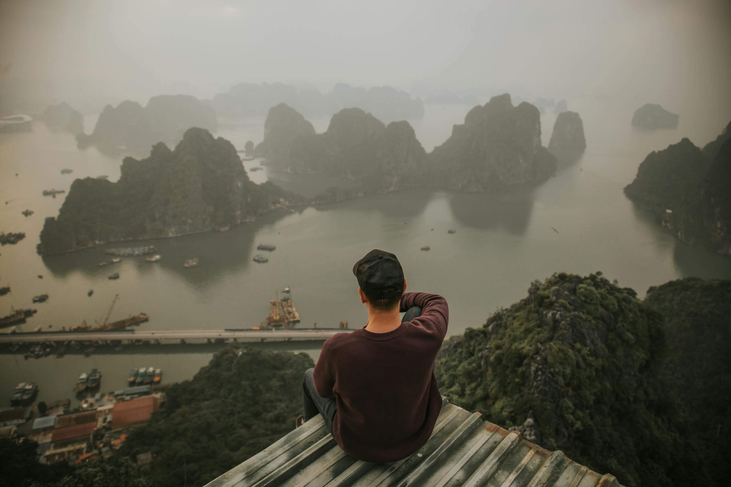A person sits overlooking the misty, picturesque Ha Long Bay in Vietnam.