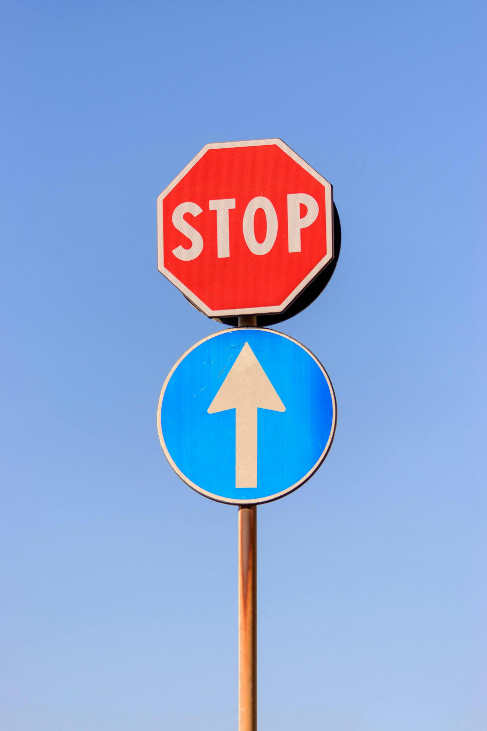 A red stop sign and blue forward arrow against a clear blue sky. About MappedAtlas is a movement system guide making your journey, uncomplicated