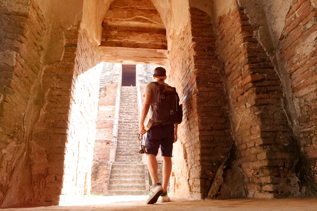 A traveler ascends stairs in a historic brick ruin, exuding adventure and exploration.