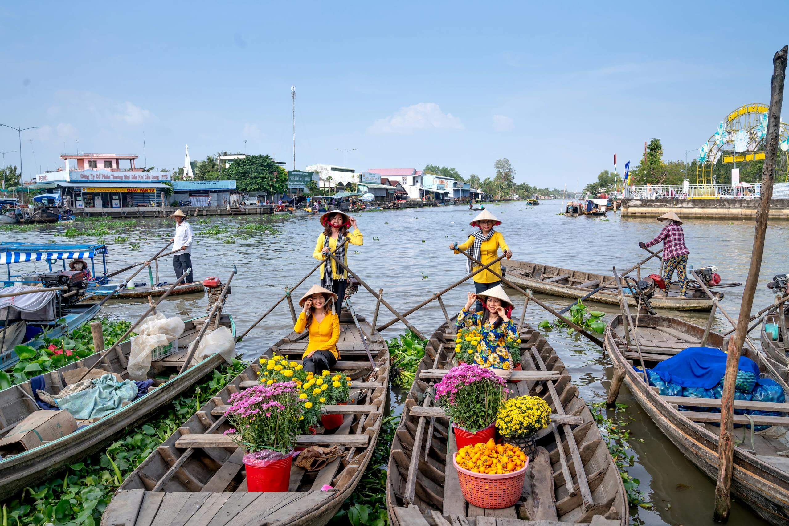 Colorful floating market in Vietnam featuring women on boats selling flowers and goods.