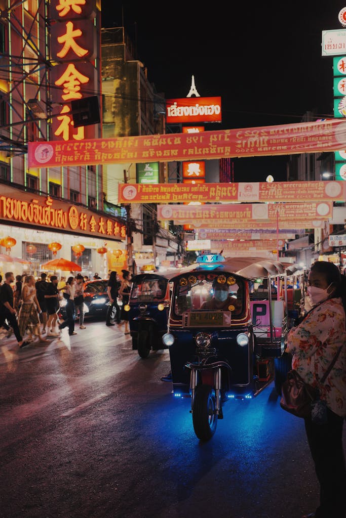 Colorful tuk-tuks and busy streets illuminate Bangkok's vibrant Chinatown at night.