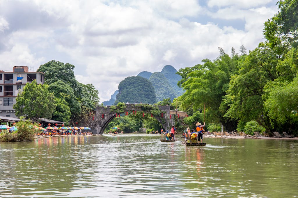 Experience traditional bamboo rafting on a picturesque river in Vietnam, surrounded by lush greenery and mountains.