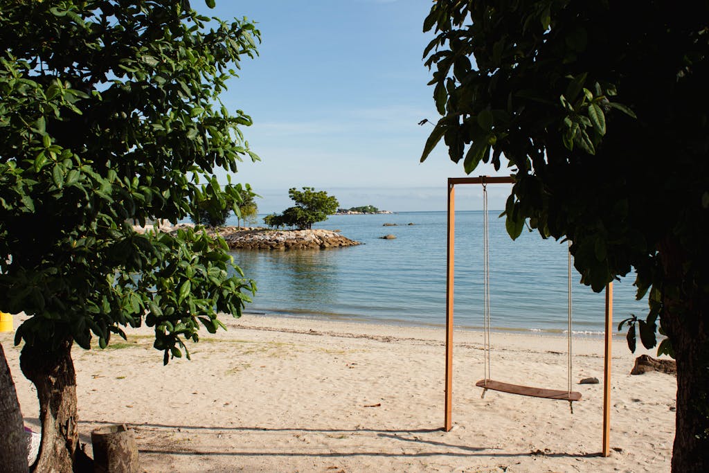 Peaceful beach scene with swing, trees, and ocean view in George Town, Malaysia.