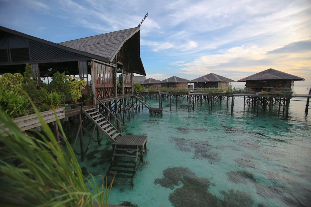 Scenic view of overwater bungalows on stilts in Malaysia with turquoise waters and clear blue skies.