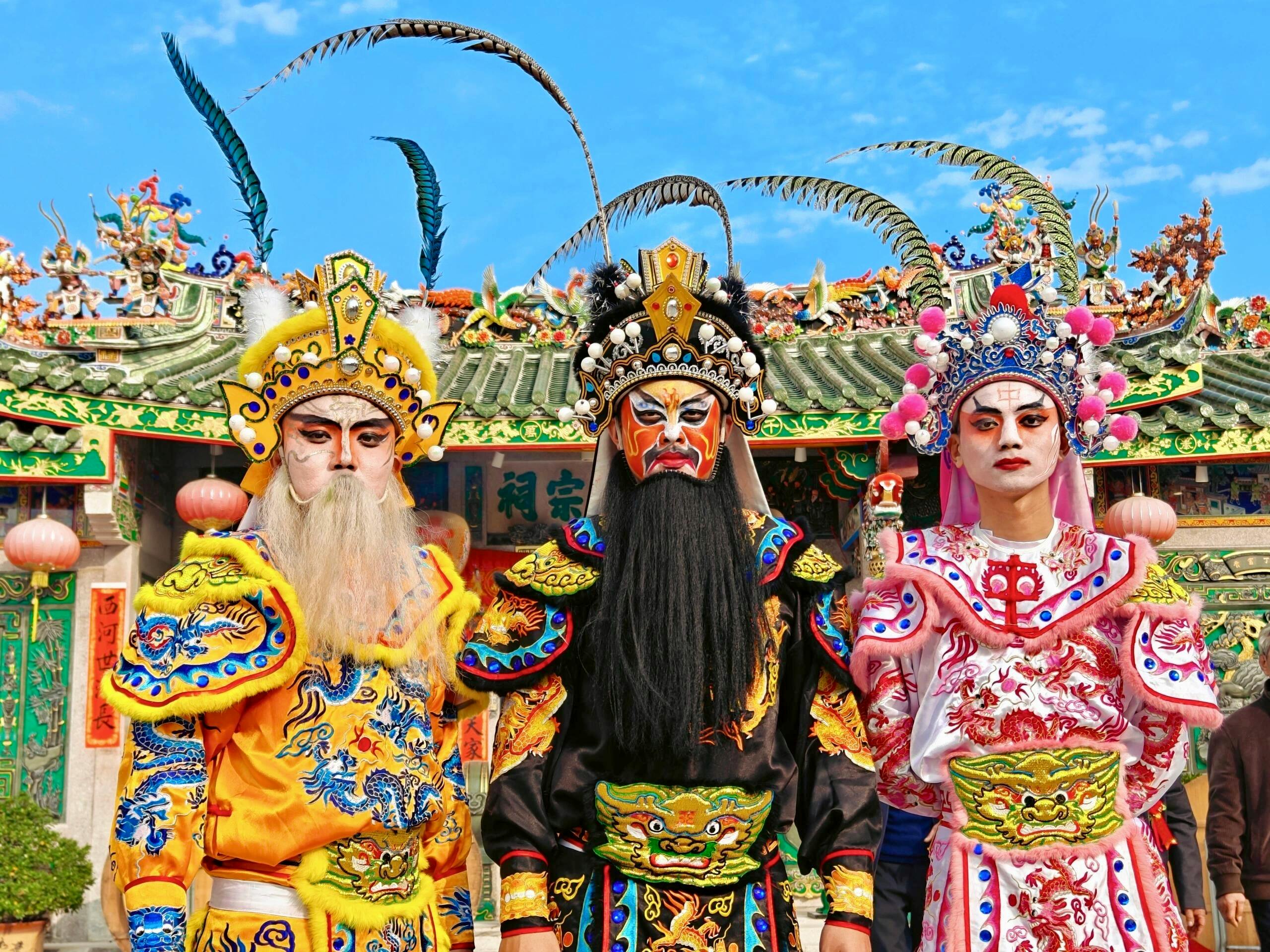 Vibrant display of traditional Chinese opera costumes and makeup against ornate temple backdrop.